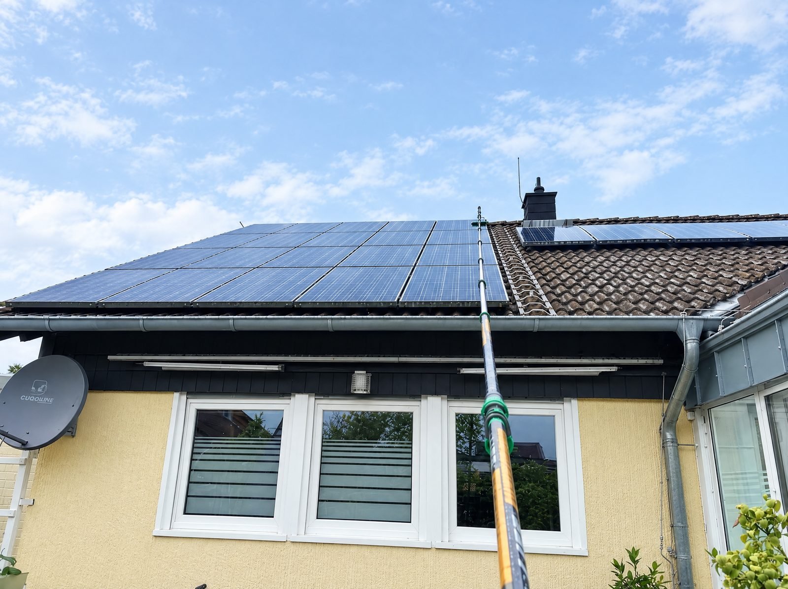 Solarpanel-Reinigung: Teleskopstange an einer Solaranlage auf einem Wohnhausdach